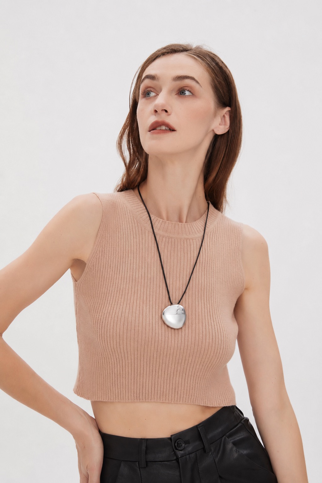 AI pendant worn with hand-on-waist pose and minimal studio styling