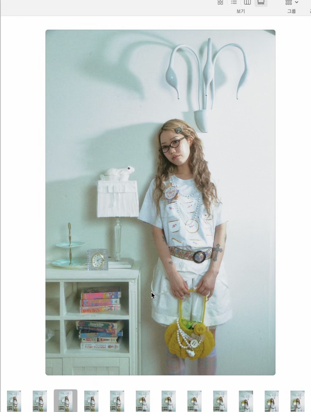 Photo-selection screen showing a model in a pale blue T-shirt and white skirt holding a yellow crochet handbag.