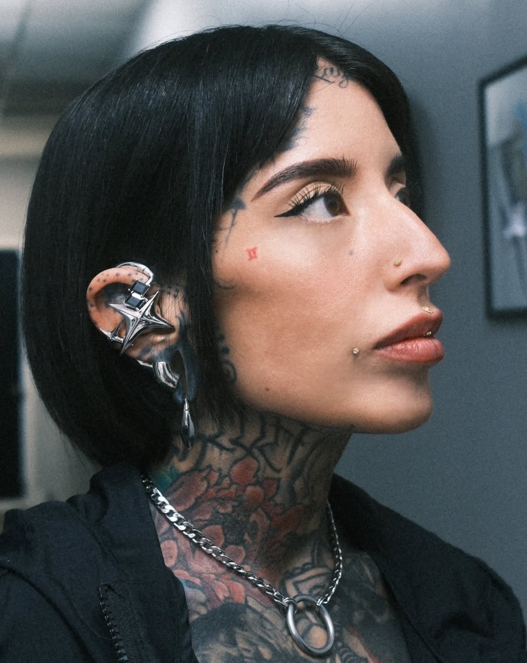 Side-profile portrait of a wearer in black styling with a silver NEBULA-style sculptural open earphone.