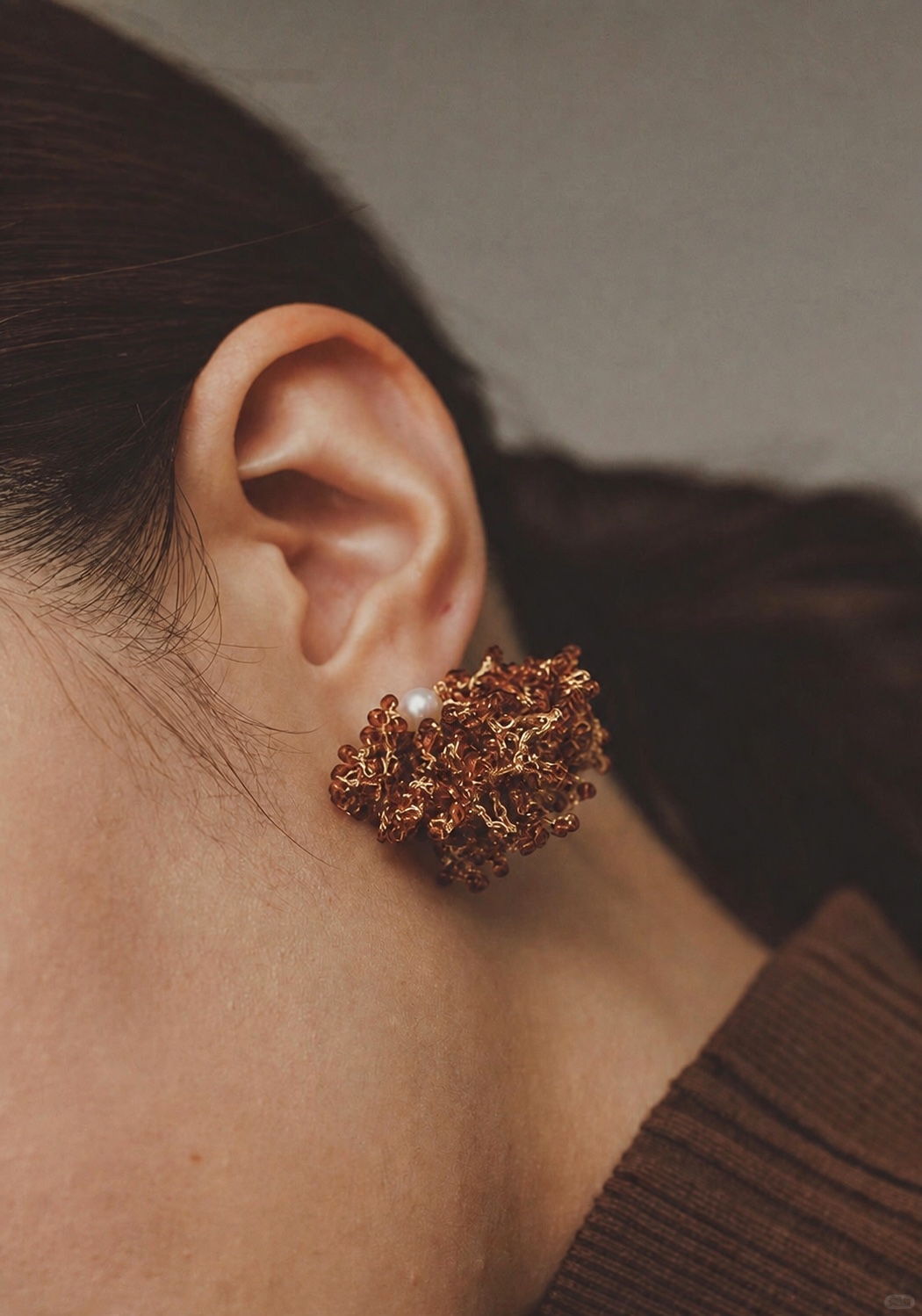 FUA gold beaded statement earring in a close-up portrait