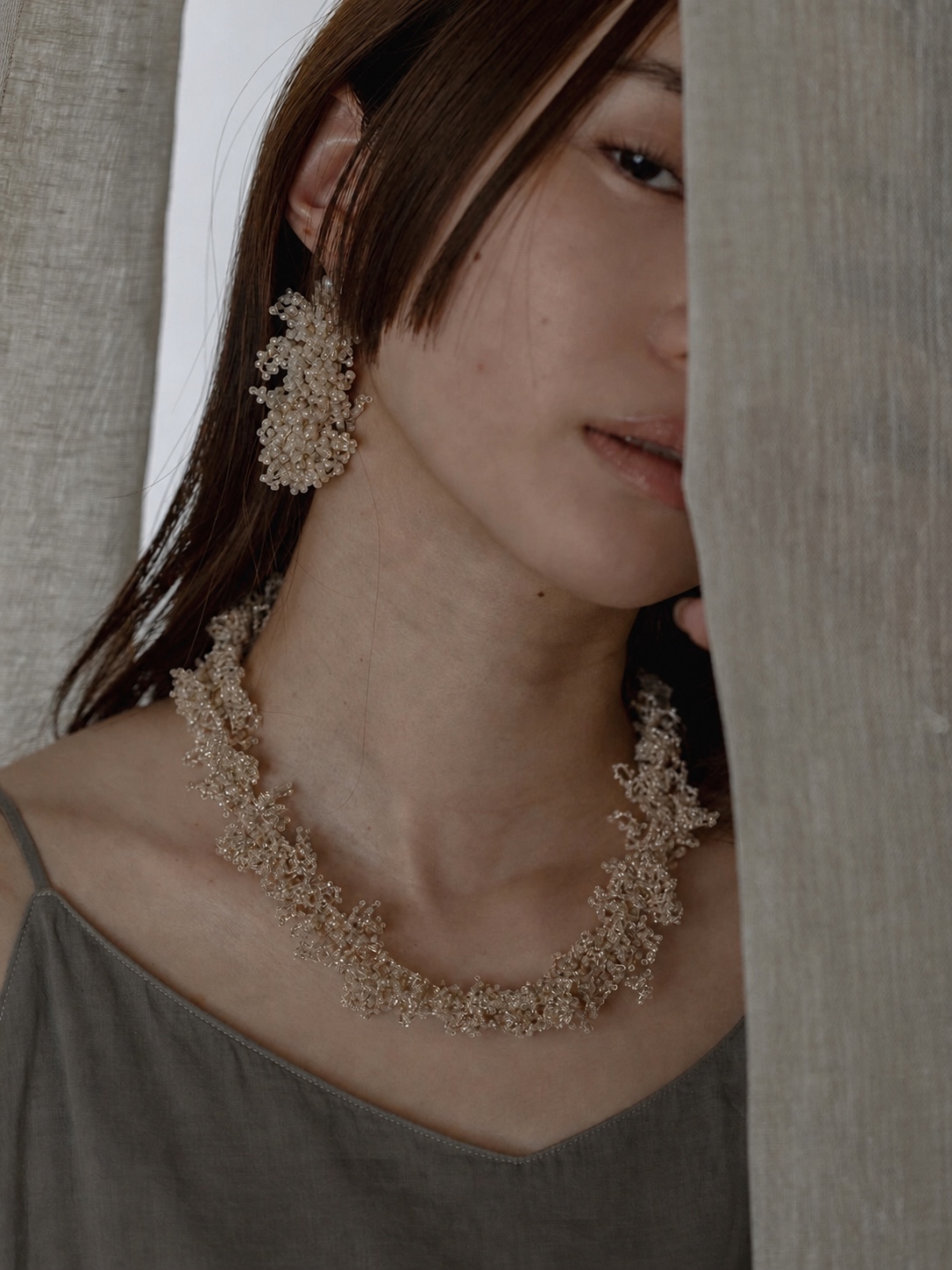 FUA silver beaded earrings worn against a green background