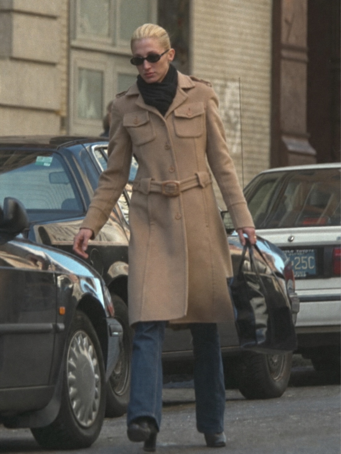 Carolyn Bessette Kennedy camel coat outfit with sunglasses and minimalist 90s styling