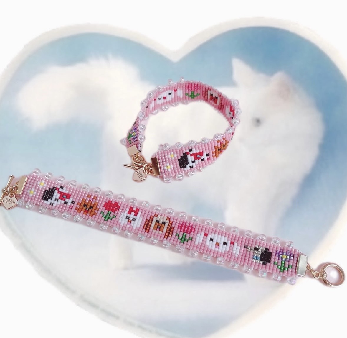 Two pink woven-bead bracelets with tiny multicolored motifs arranged on a heart-shaped cat dish.