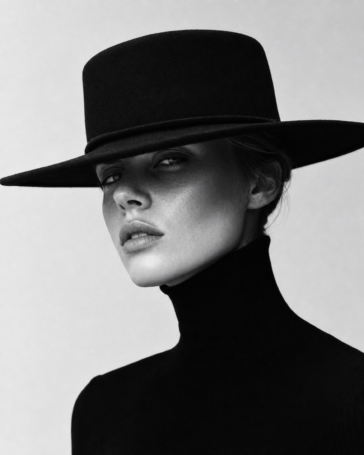 Wide black headwear frames the face and extends the outfit's horizontal geometry