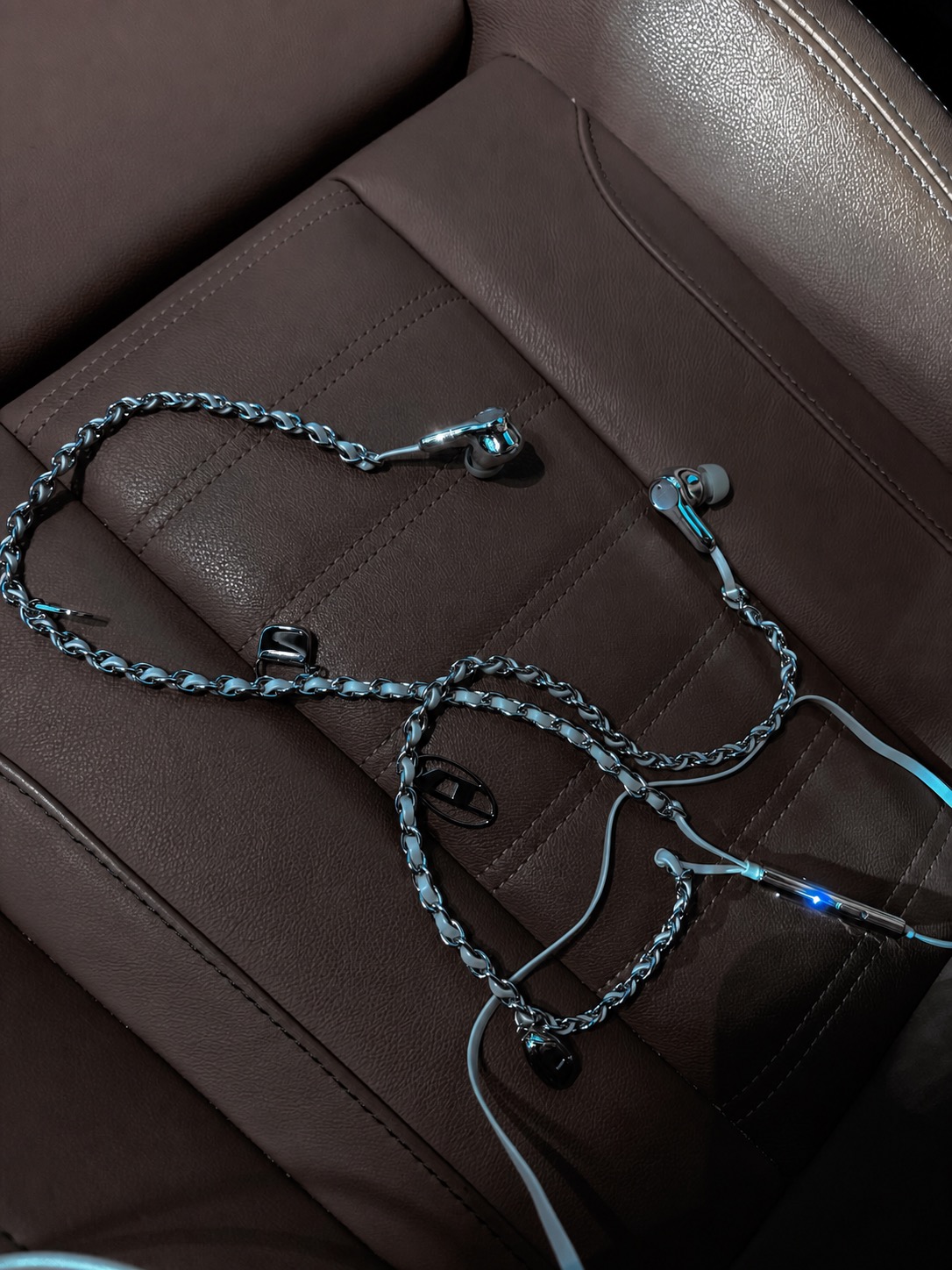 Diesel earphones with a blue-toned chain cable on a brown leather surface