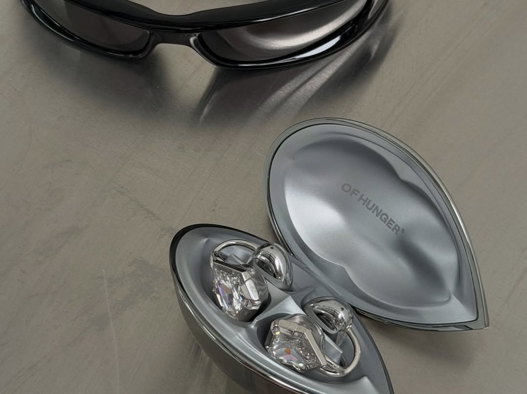 A jewelry earbud reading as a drop earring from a three-quarter profile at arm's length.