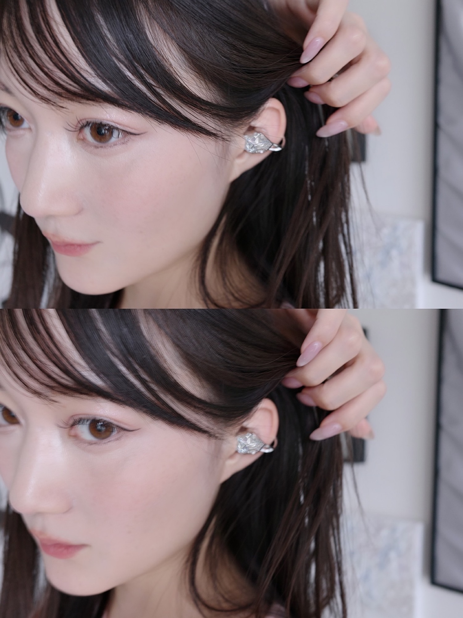 Dark-haired wearer lifting her hair to show a faceted silver open earphone.