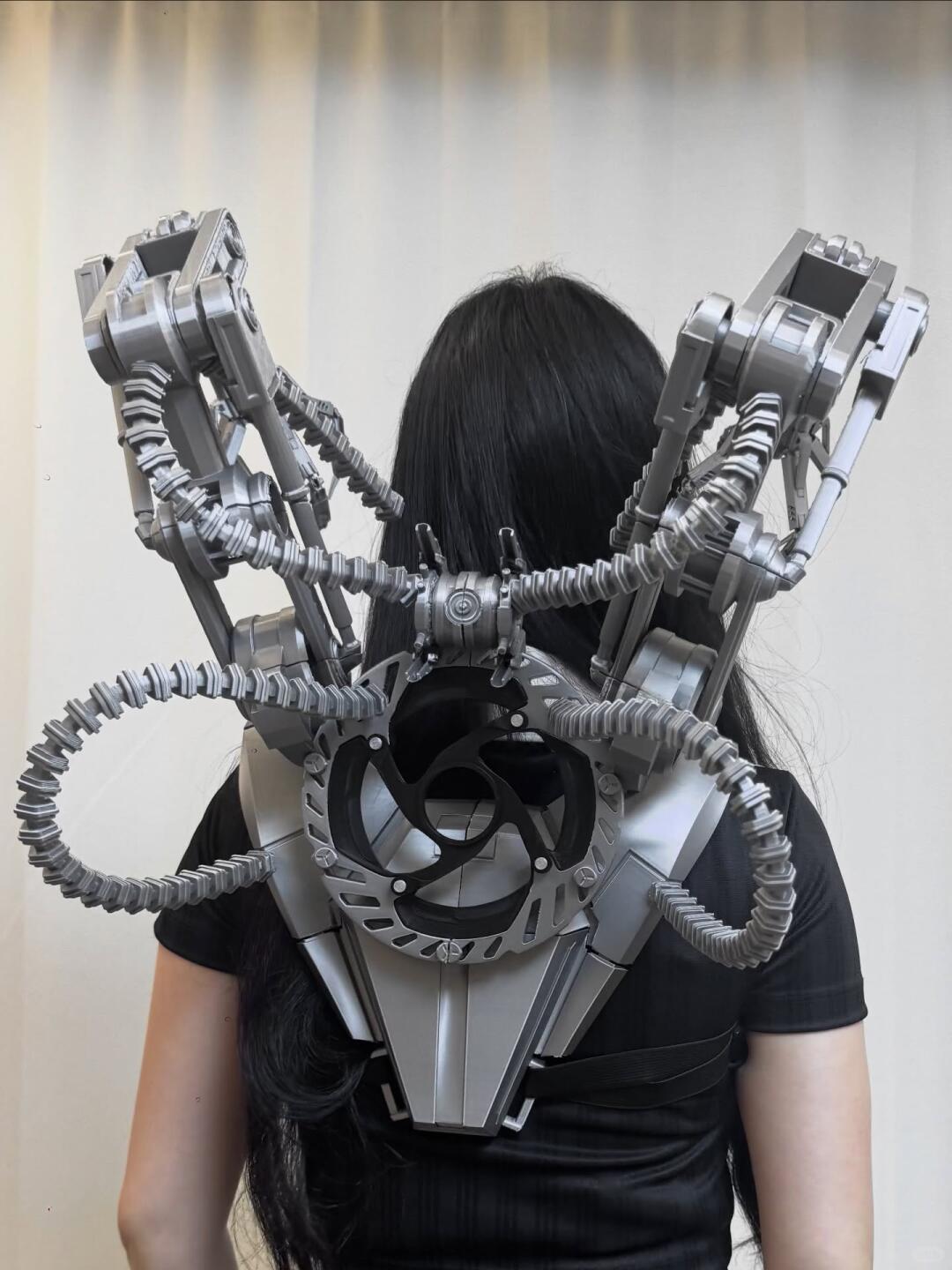 Silver articulated mechanical rig extending from the wearer's back