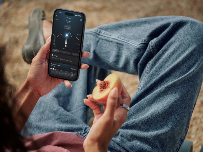 Oura health insights displayed on a phone while a person checks a wearable health experience.