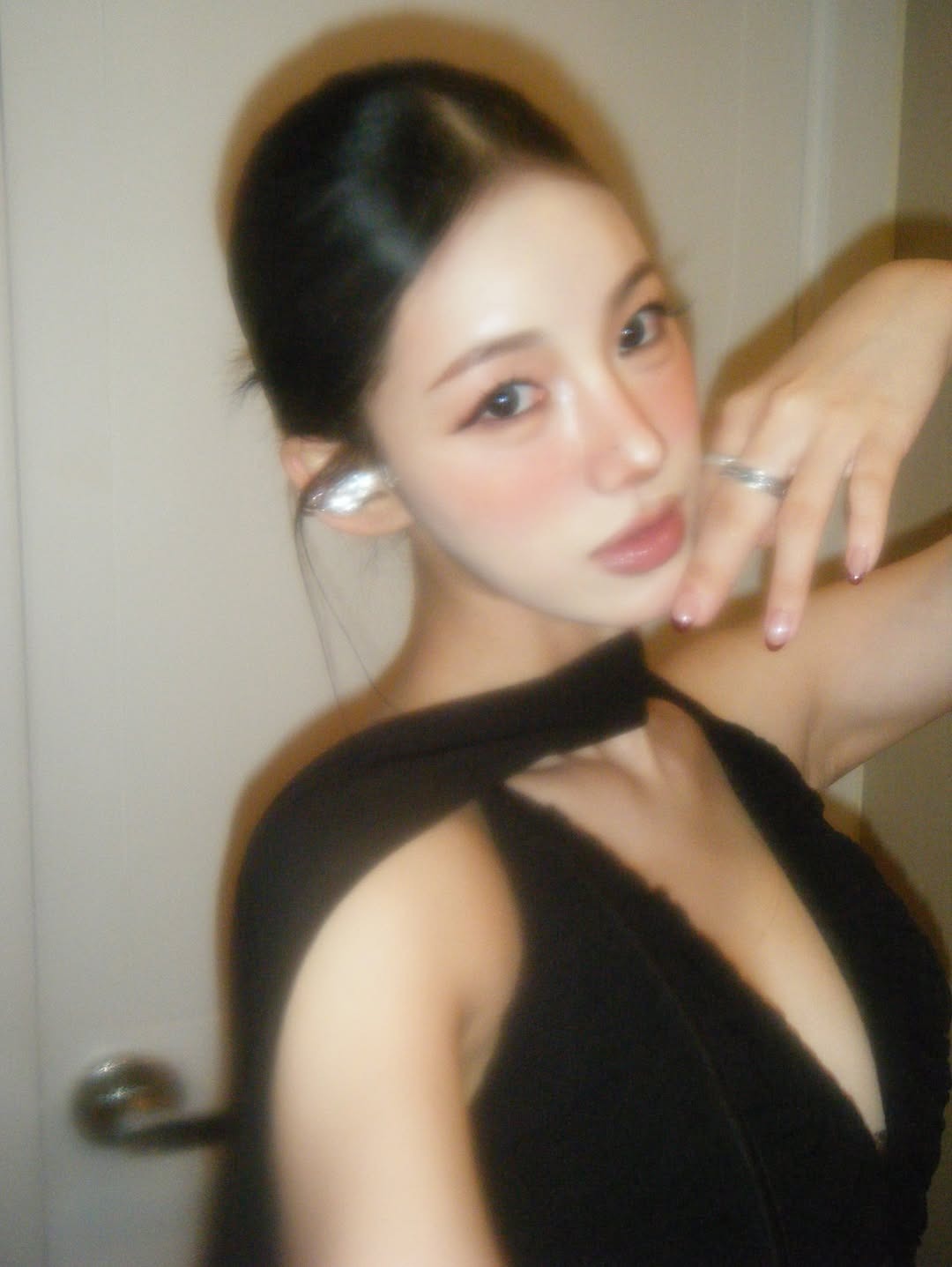 Side-profile portrait of a wearer in black styling with a silver sculptural open earphone.