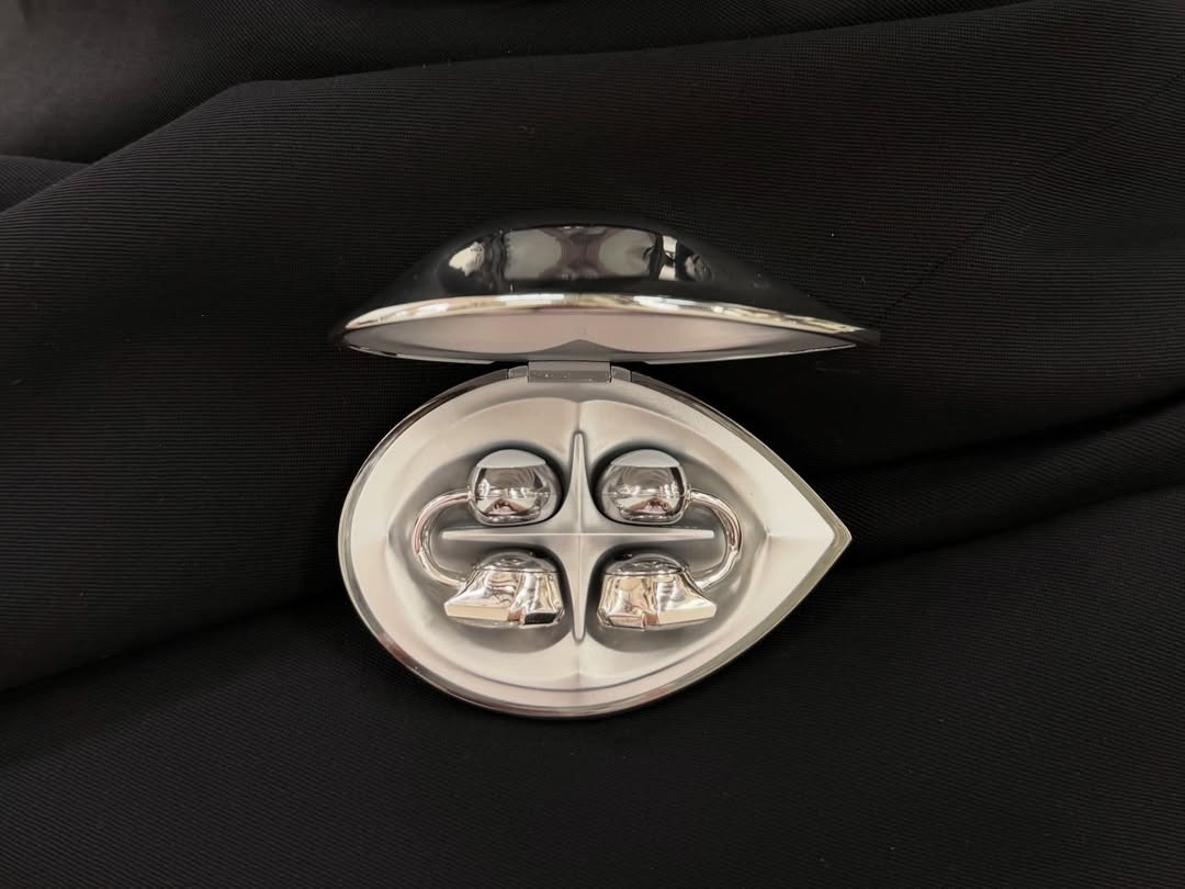 A silver gemstone-style open earphone case held in hand with the product visible inside.
