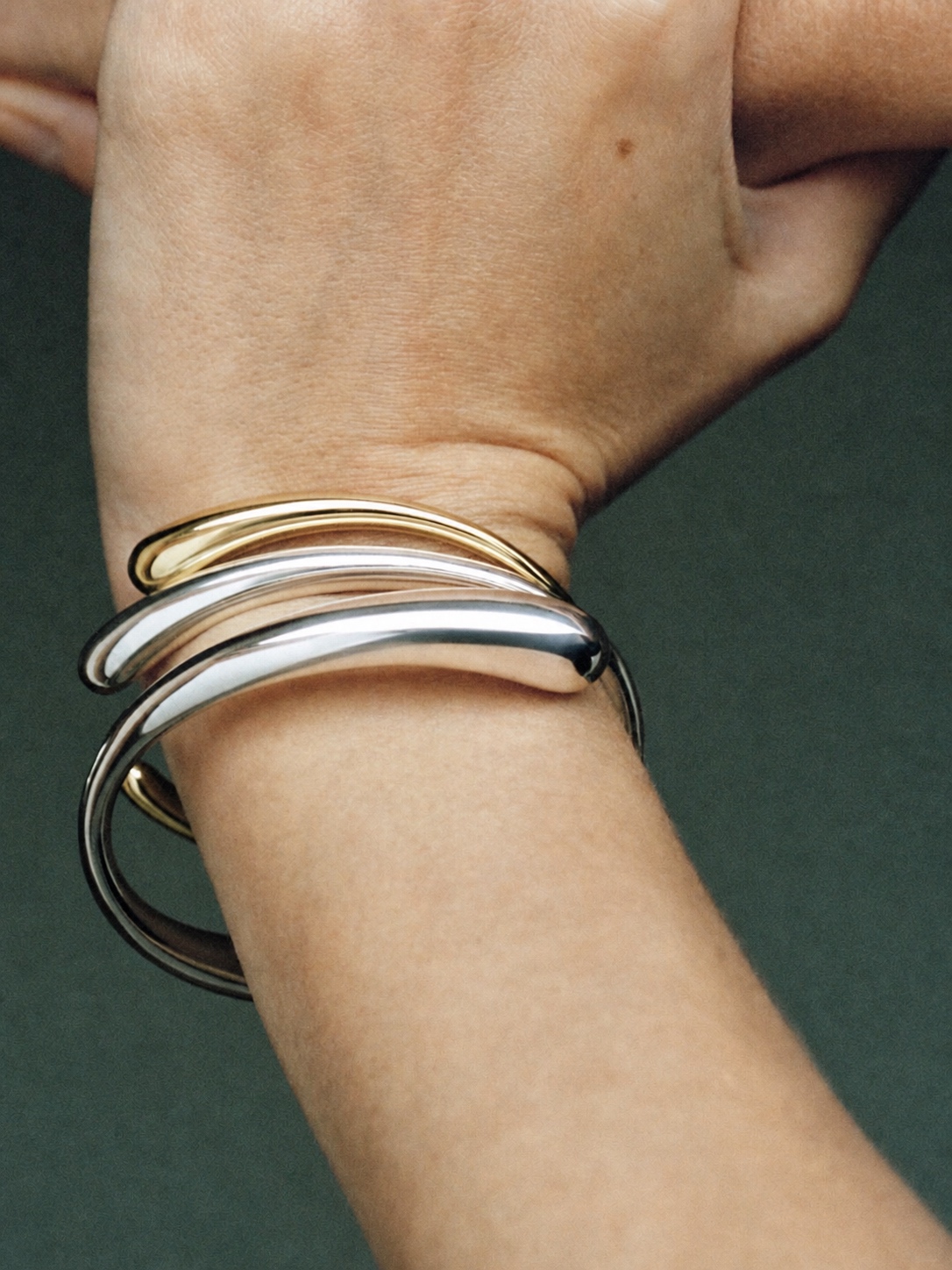 Stacked silver and gold Georg Jensen bracelets on a wrist