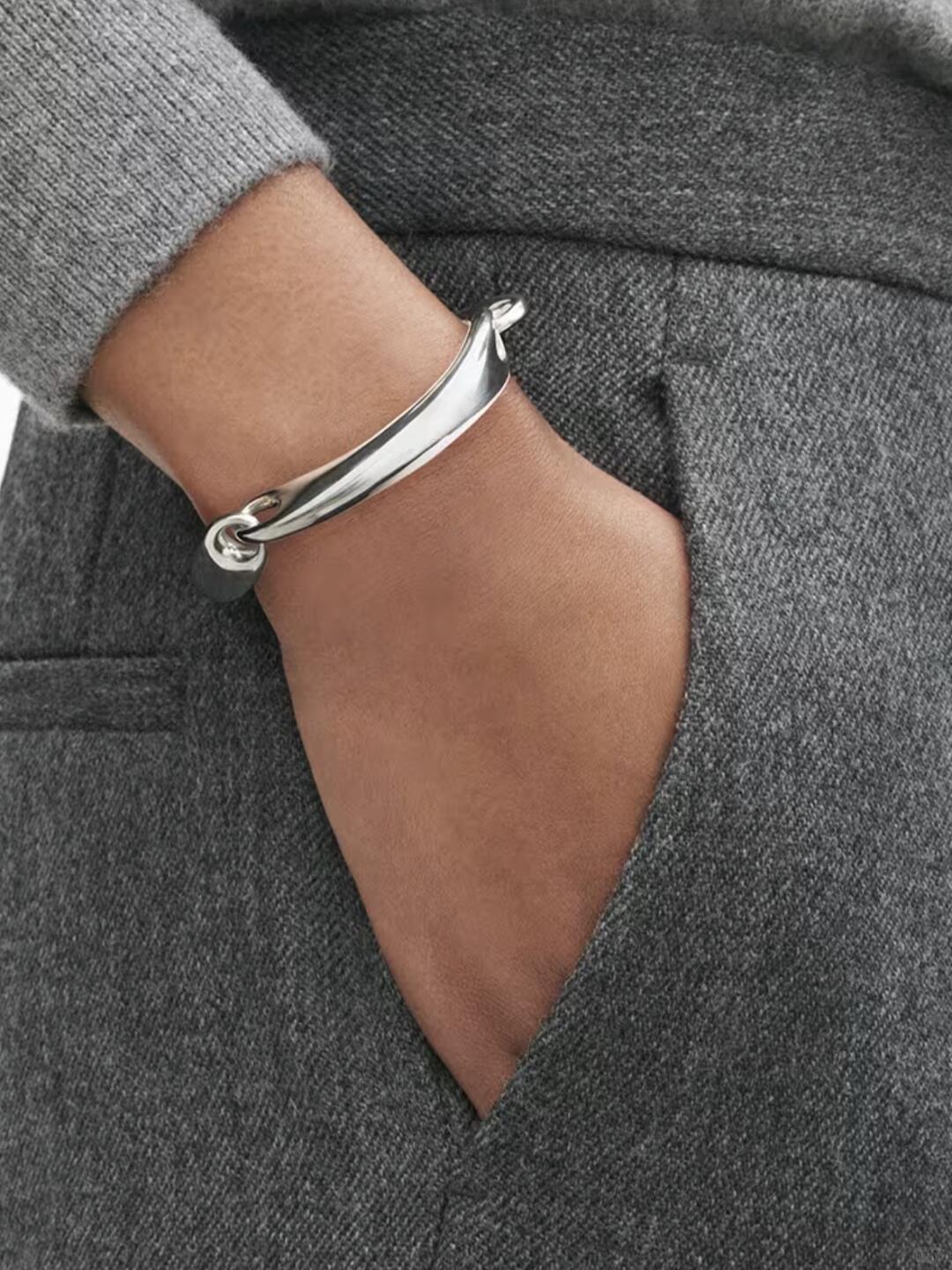 Rounded silver Georg Jensen bracelet over grey knitwear