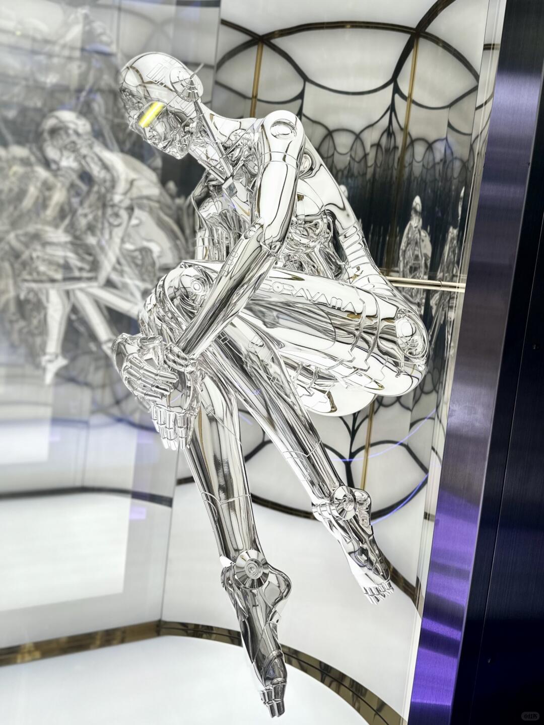 Silver Sorayama robot crouching inside mirrored exhibition structure