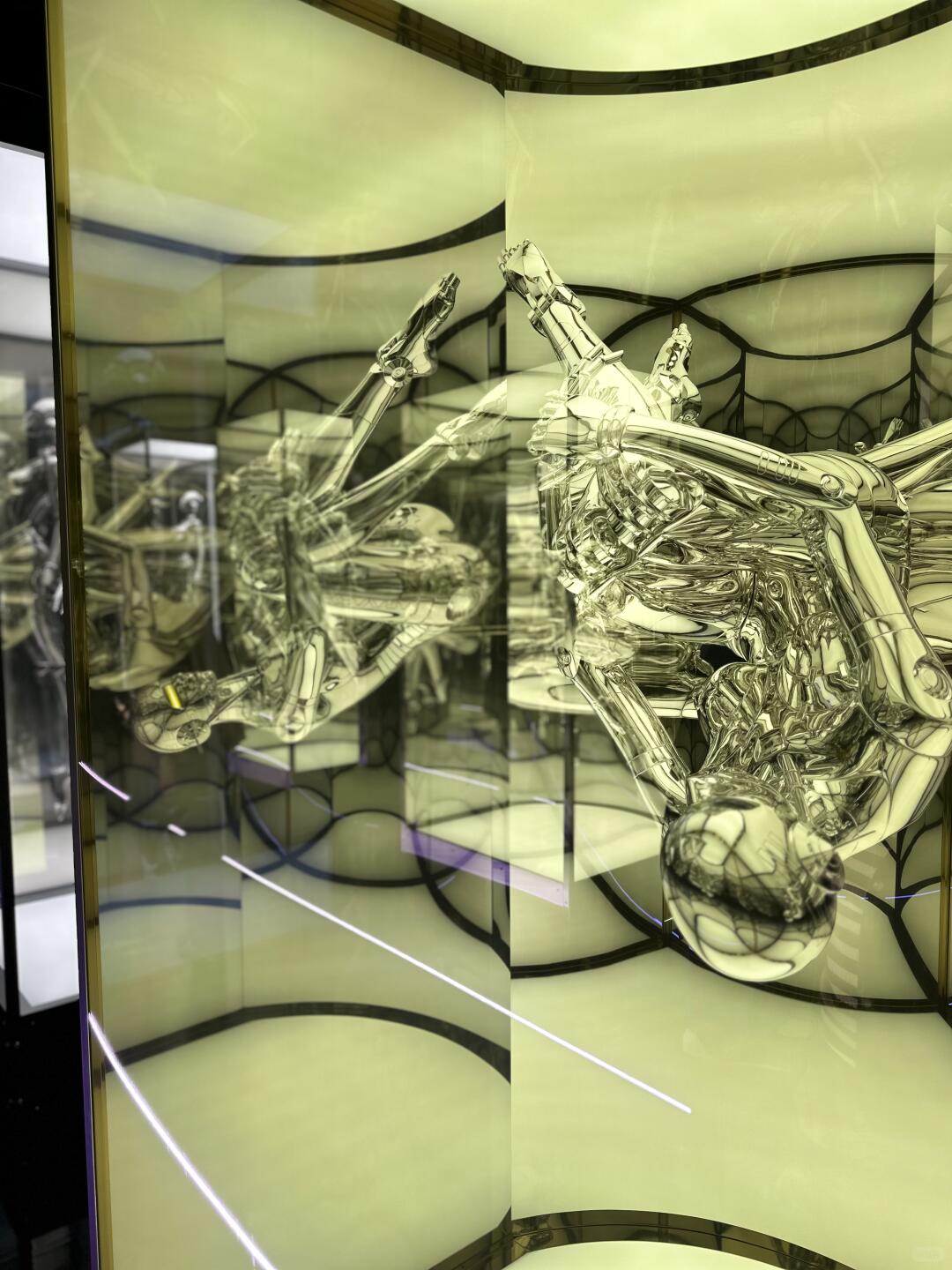Silver chrome robot figure suspended sideways in illuminated mirrored case