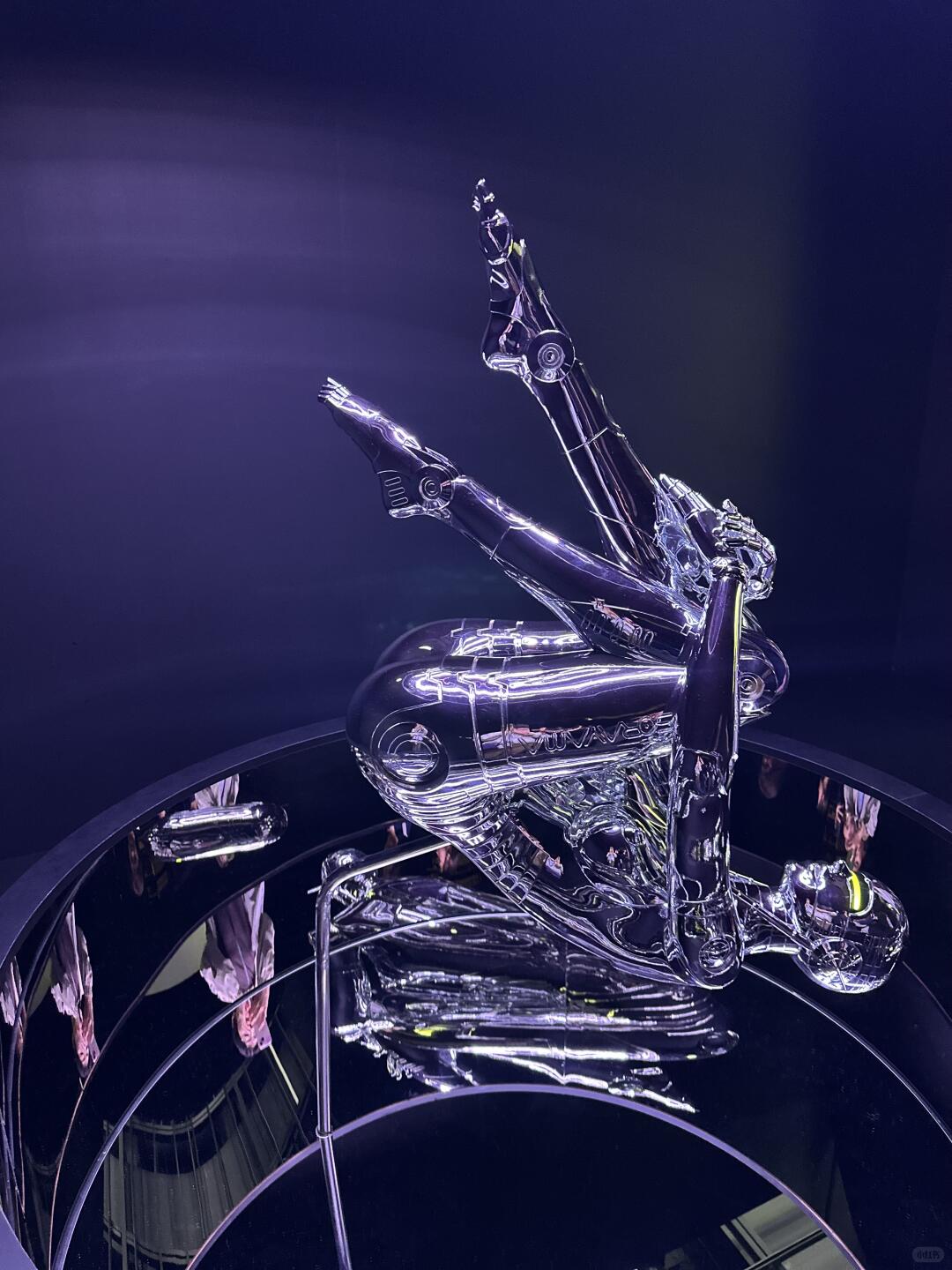 Purple-lit chrome robot figure displayed above a circular installation