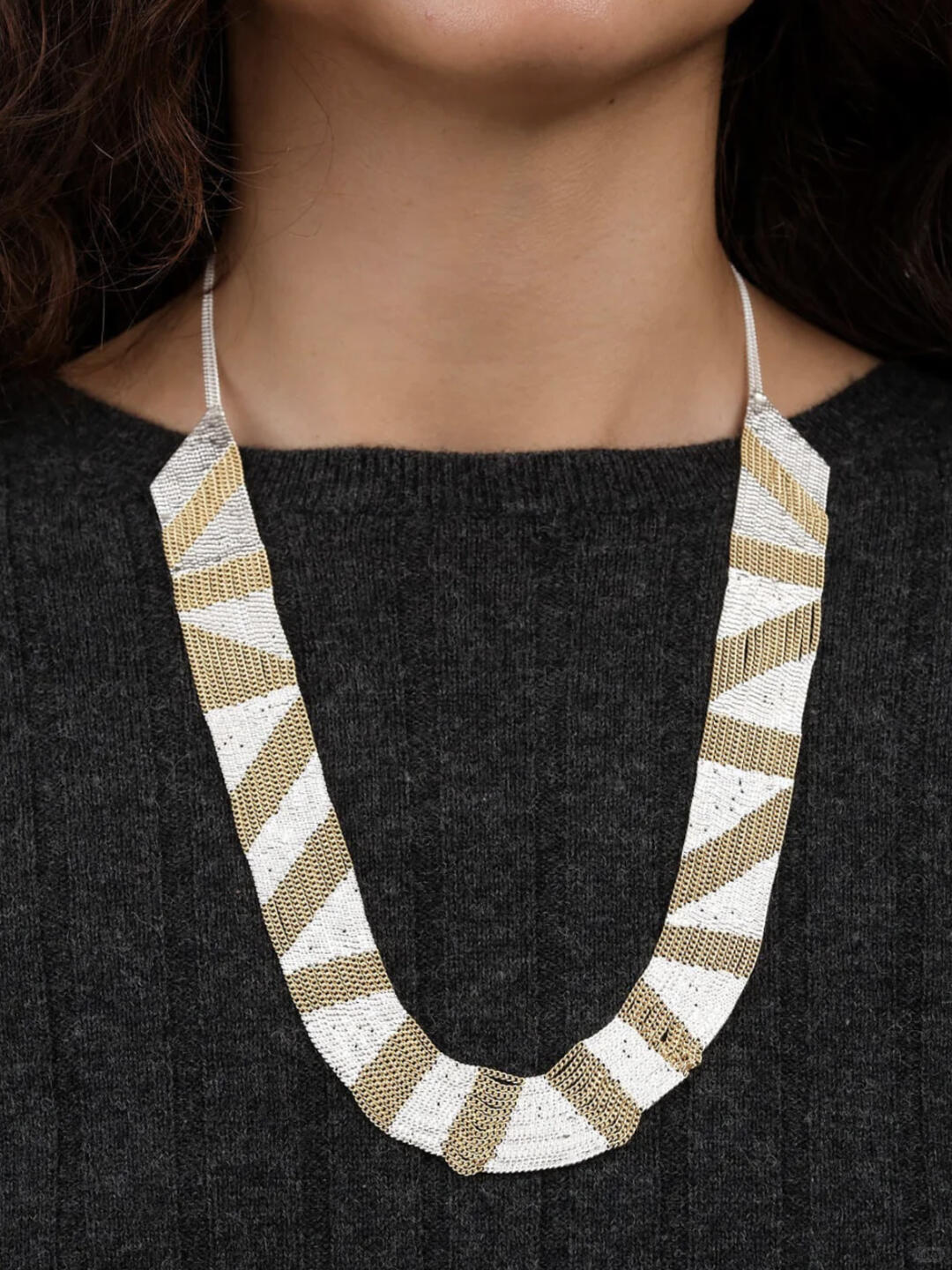 White and gold Hannah Keefe chain necklace against dark knitwear