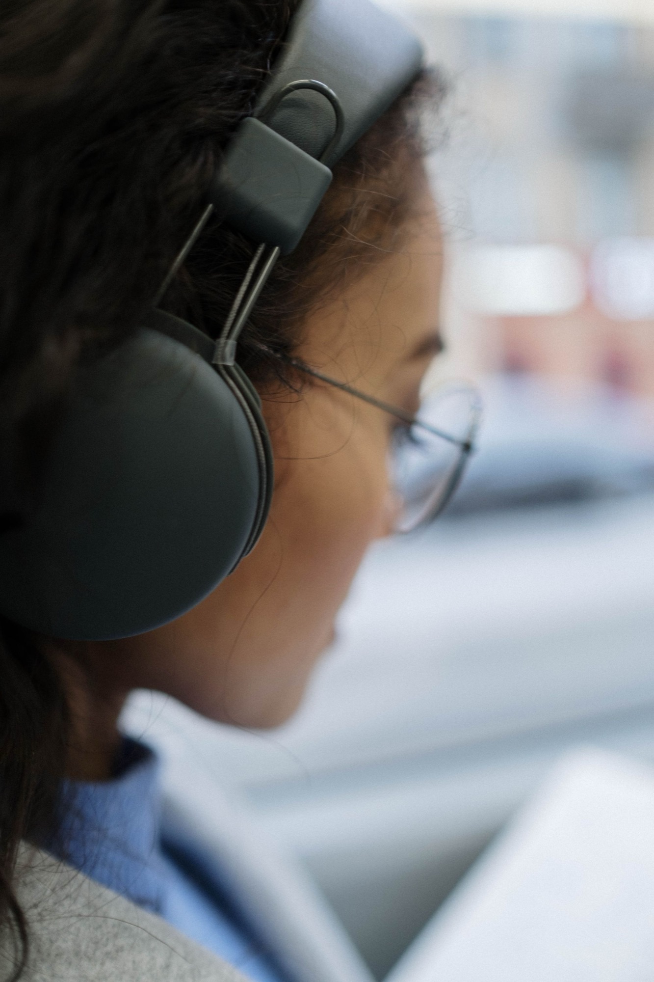 Black headphones blended into dark hair and a dark outfit — the device becomes part of the texture.