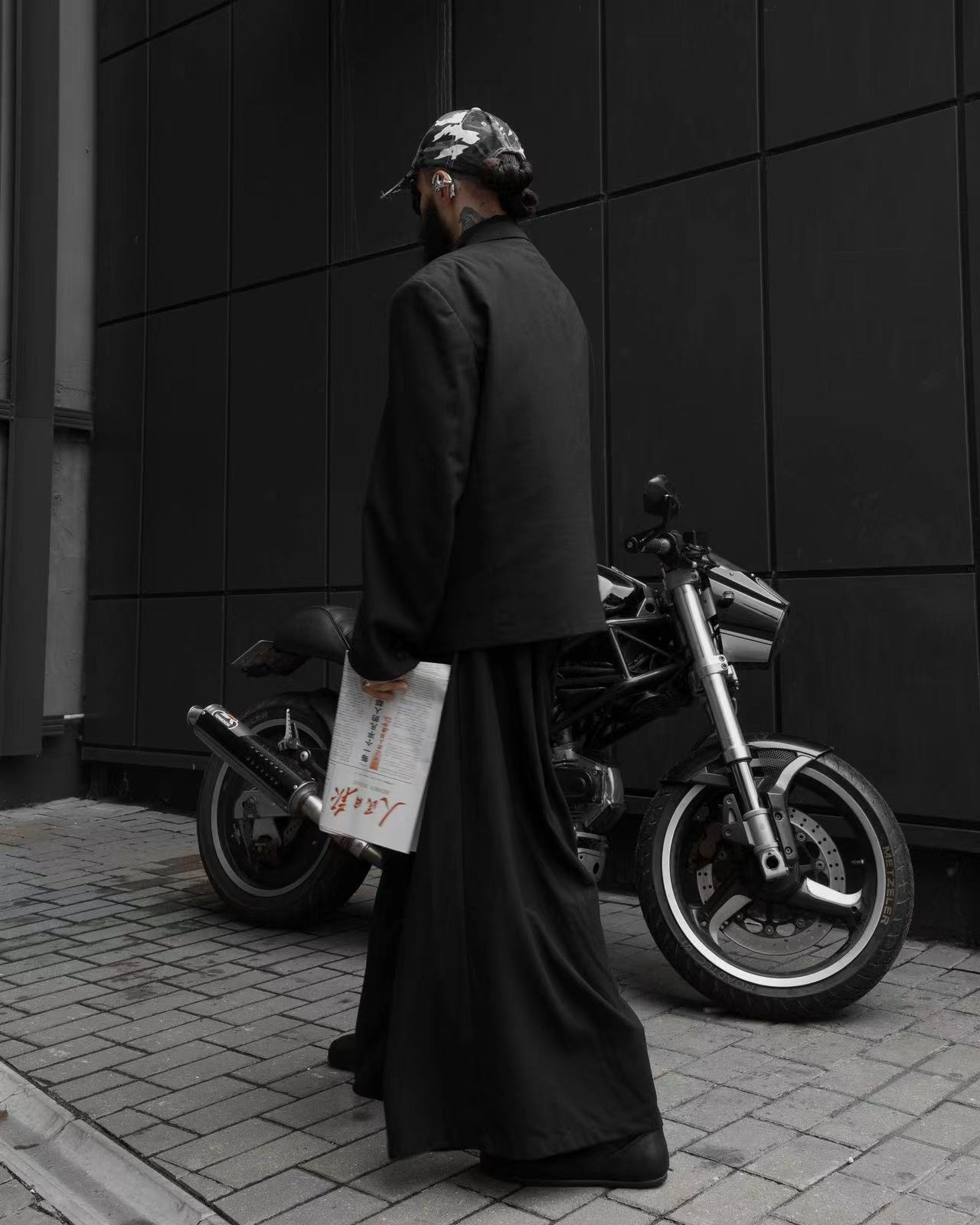 A sculptural silver earphone as the single contrast point against a minimal grey outfit.