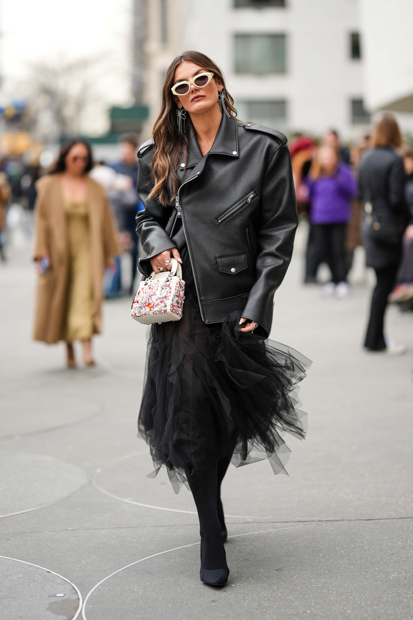Oversized structured black leather jacket worn over a voluminous black tulle skirt