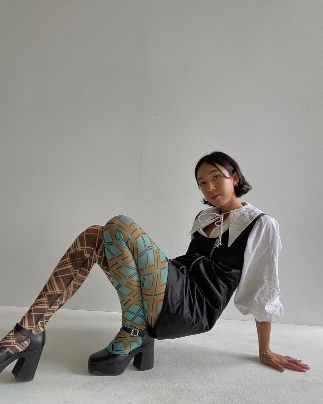 Two different printed tights paired with a black mini dress and platform Mary Jane shoes