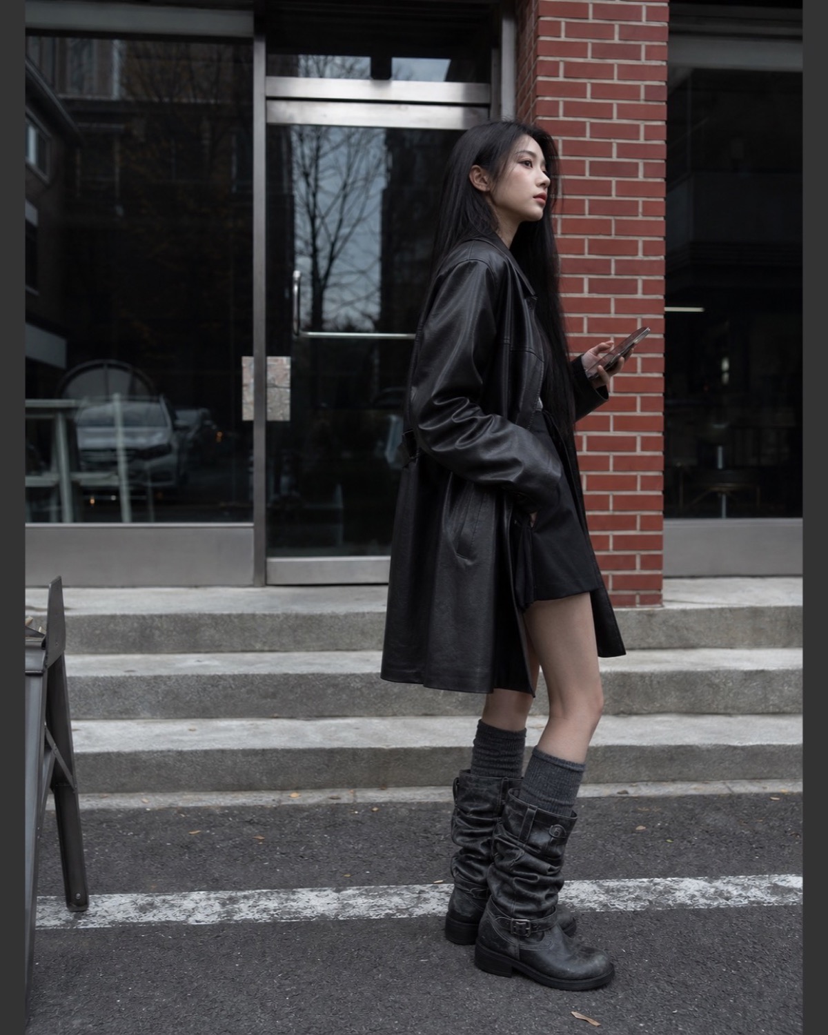 Tonal black outfit combining matte leather, ribbed socks and worn slouch biker boots
