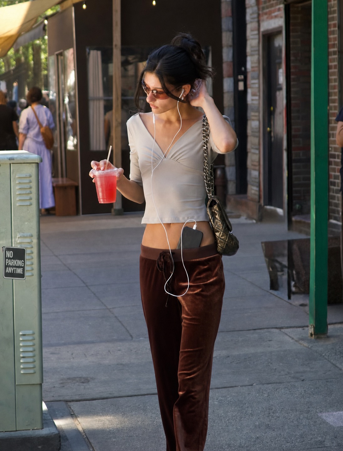 A street outfit with a white top, brown trousers, wired earbuds, and black accessories.