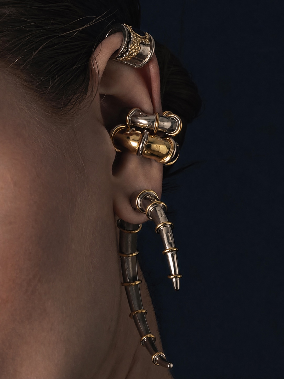 Gold and silver Jaagravii ear cuff jewelry on a dark background