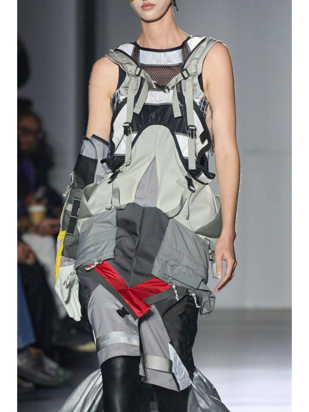 Back view of a grey Junya Watanabe SS2025 look with layered straps and an industrial train