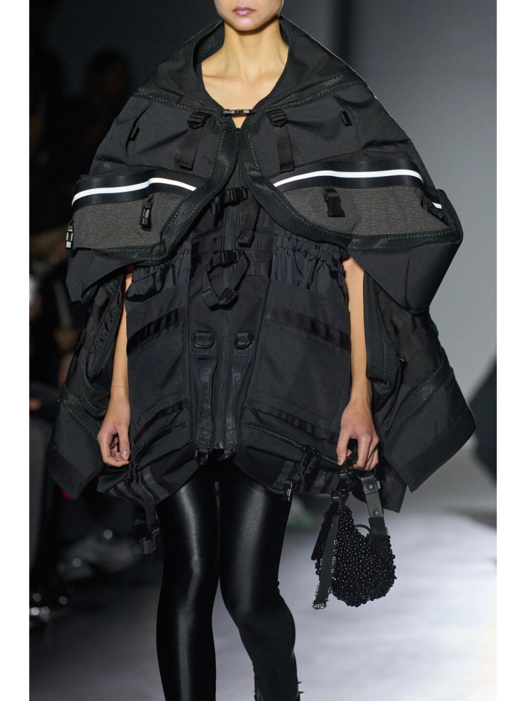 Black Junya Watanabe SS2025 hooded look with structured shoulders and glossy leggings
