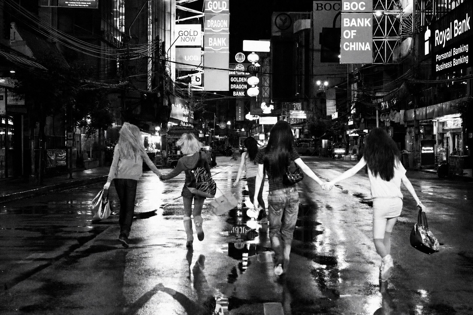 Black-and-white rainy city street scene with friends running together