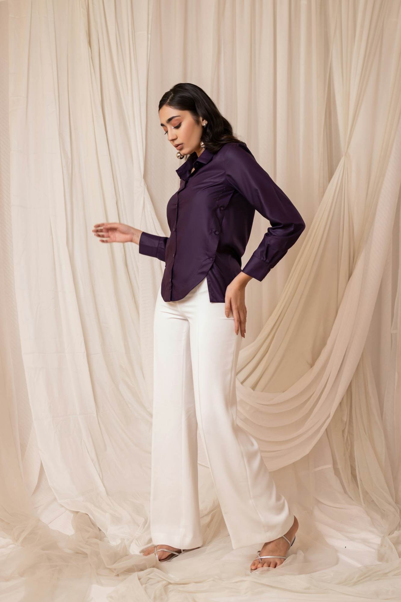 Deep purple satin shirt paired with flowing white trousers