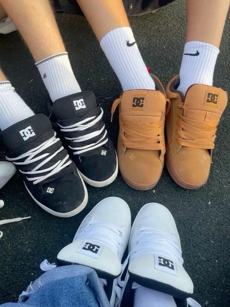 Overhead view of three pairs of padded DC sneakers in black, tan and white, worn with white socks or blue jeans.