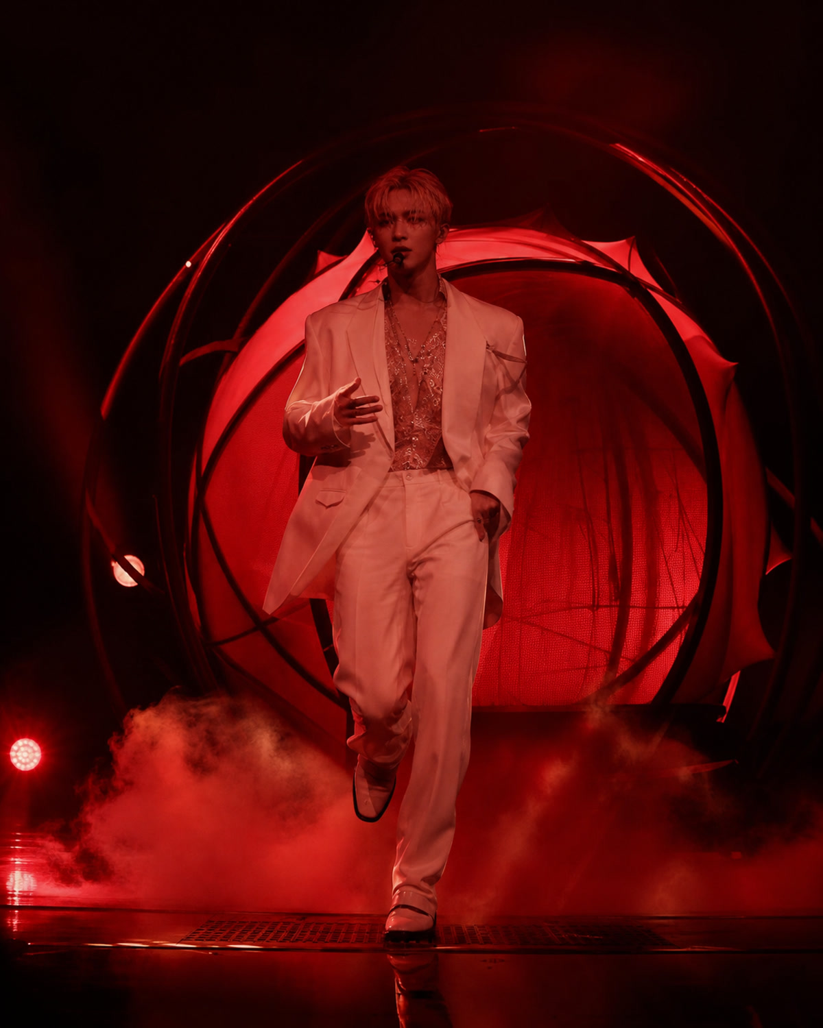 A fictional male solo performer in a white suit emerging from a red circular shell-like concert structure.