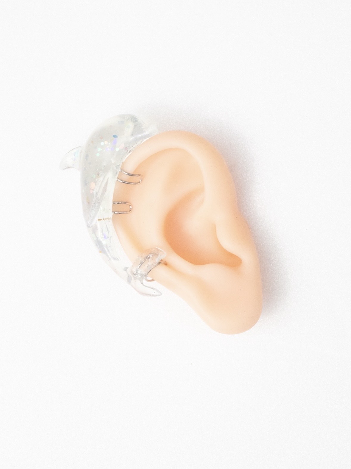 Transparent wing-shaped ear cuff with metal attachment loops displayed on a model ear.