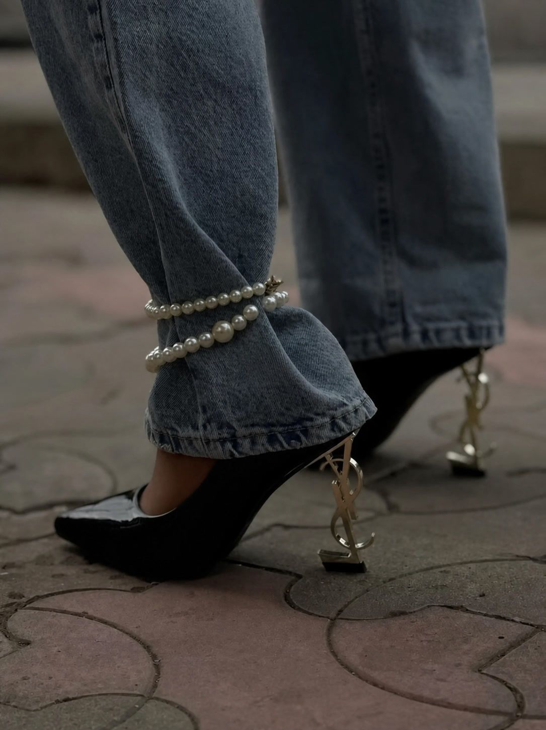 Pearl anklet styled over blue denim with black sculptural heels