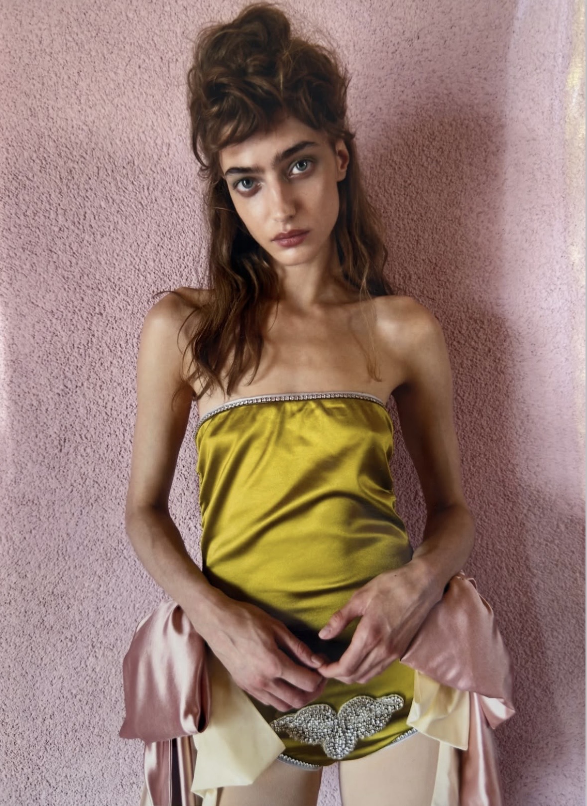 Close-up of a model in a chartreuse strapless outfit with sparkling trim, oversized pink-and-cream bows and a jeweled belt ornament.