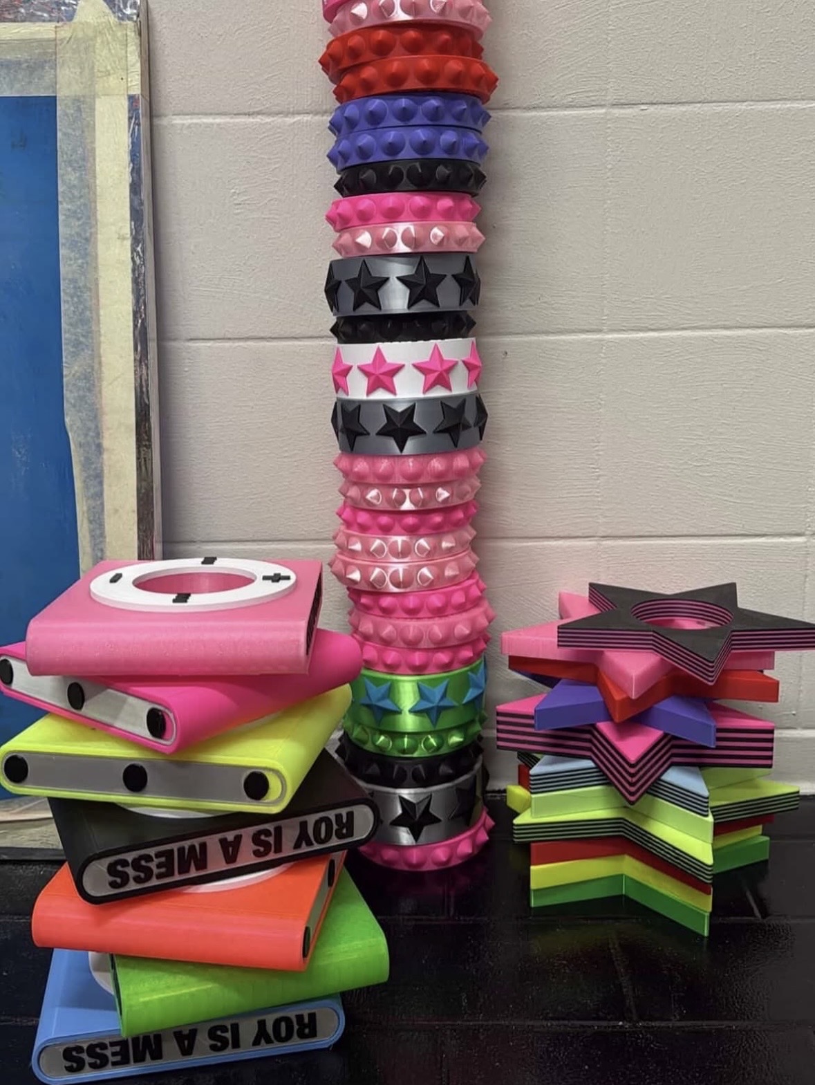 Tall stack of studded circular bracelets between piles of iPod-shaped cuffs and layered star bangles.