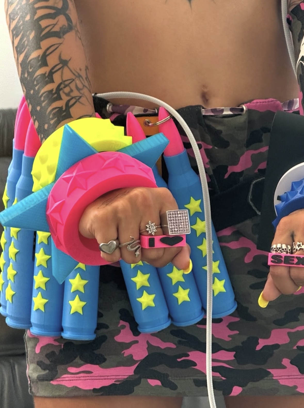 Close-up of pink, blue and yellow bangles beside a belt of oversized blue bullet shapes with yellow stars.