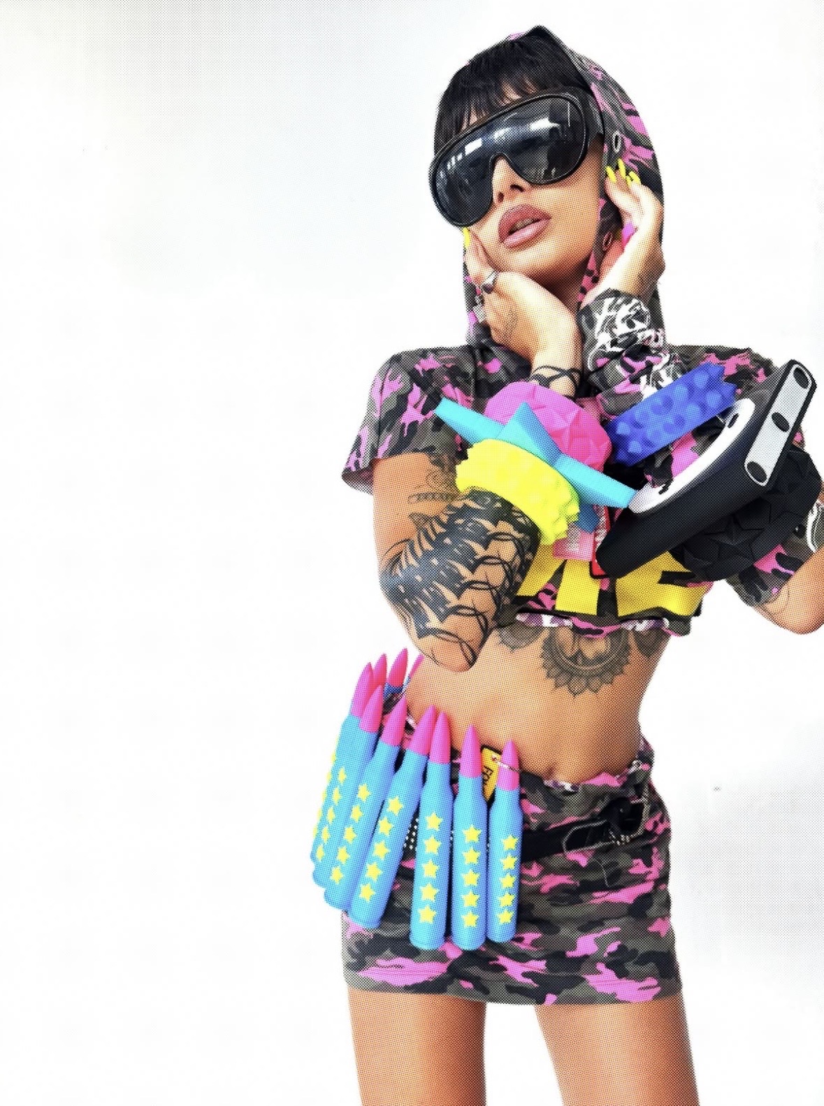 Model in black goggles and a pink camouflage hooded outfit, with neon bangles stacked around both wrists.