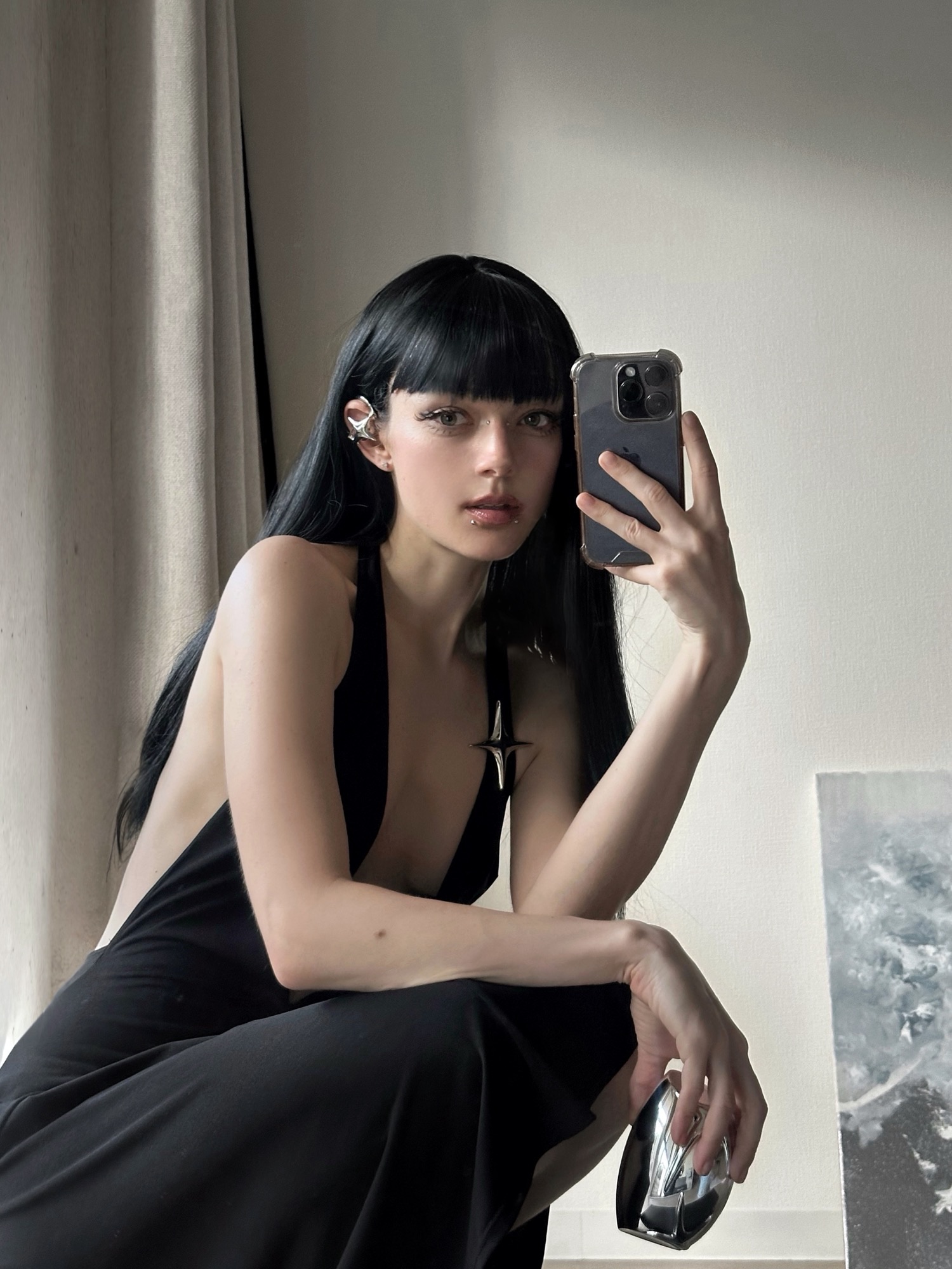 Editorial makeup portrait with a sculptural metallic ear piece and dark lip styling.
