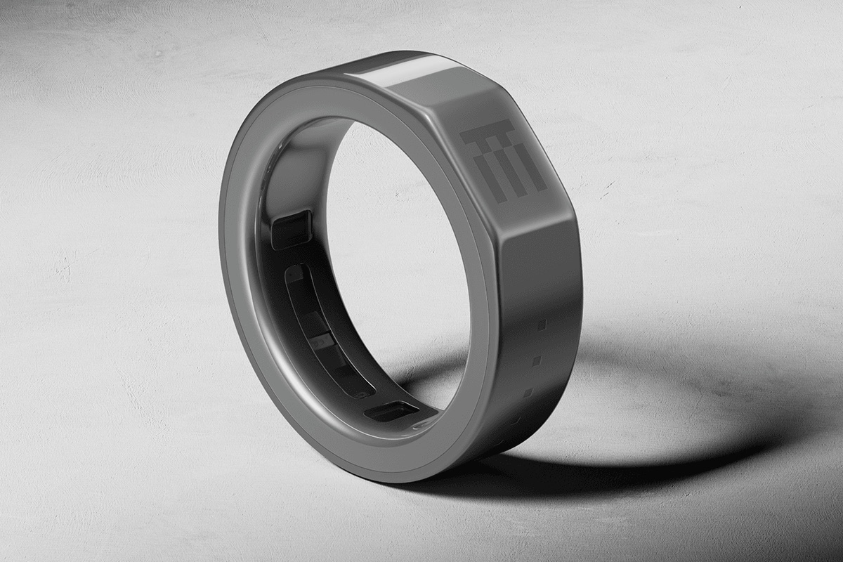 Close-up of a matte gray smart ring on a hand against black fabric.