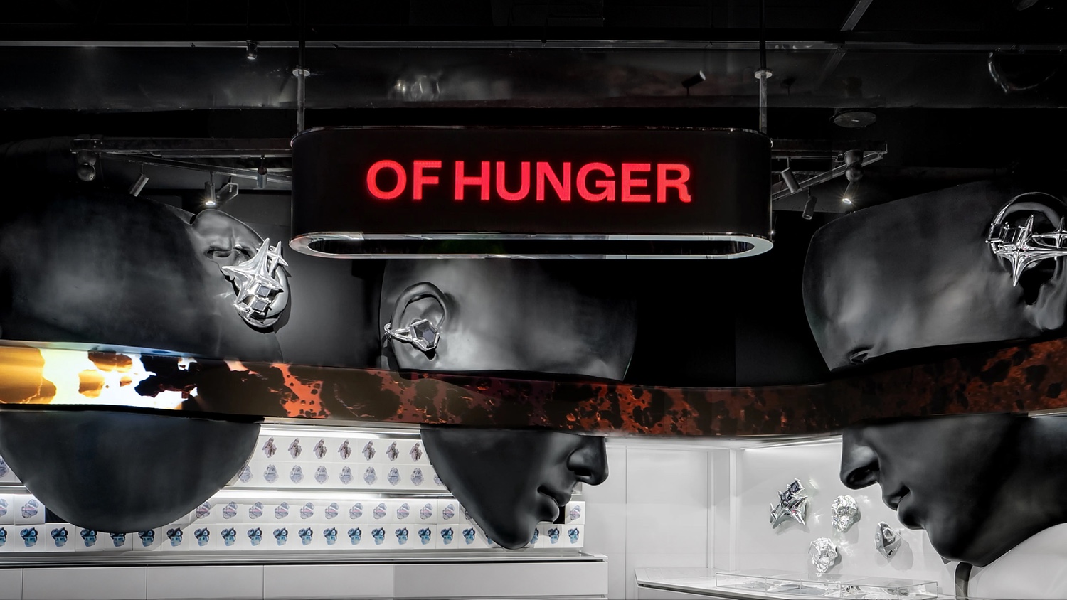 Oversized dark heads wearing enlarged ear accessories above product displays at OF HUNGER's SKP-S Beijing concept space.