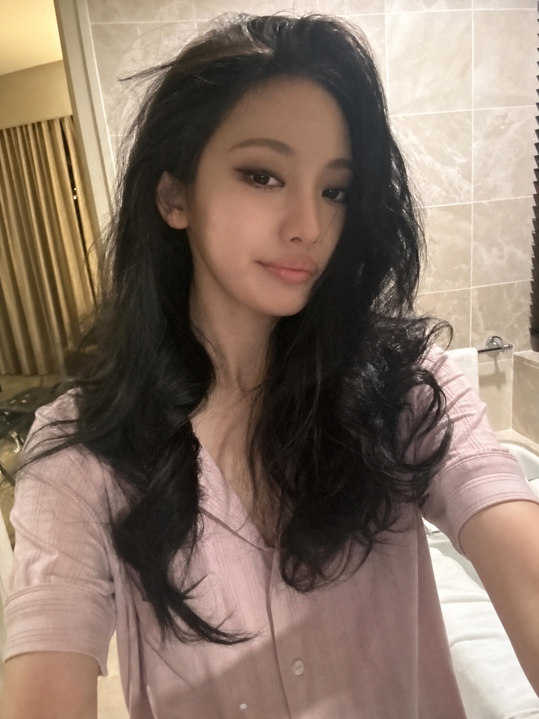 Dark feminine beauty styling with soft pink shirt and sharper siren makeup energy