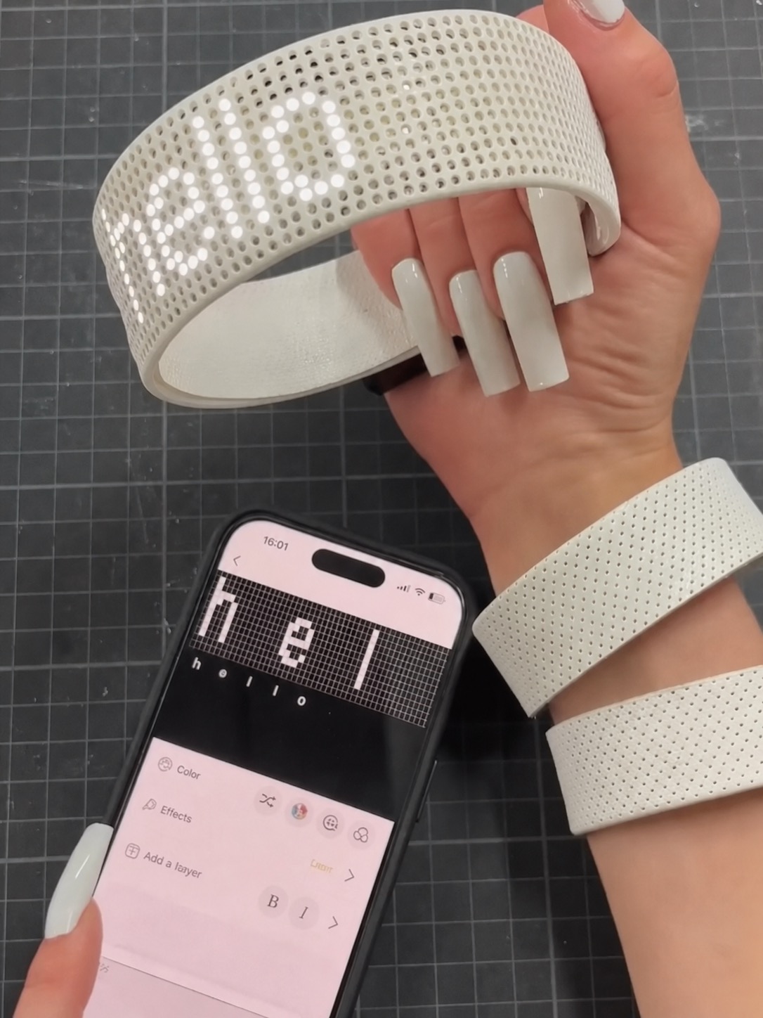 A white LED wrist object beside a phone interface, showing fashion tech as control and display.