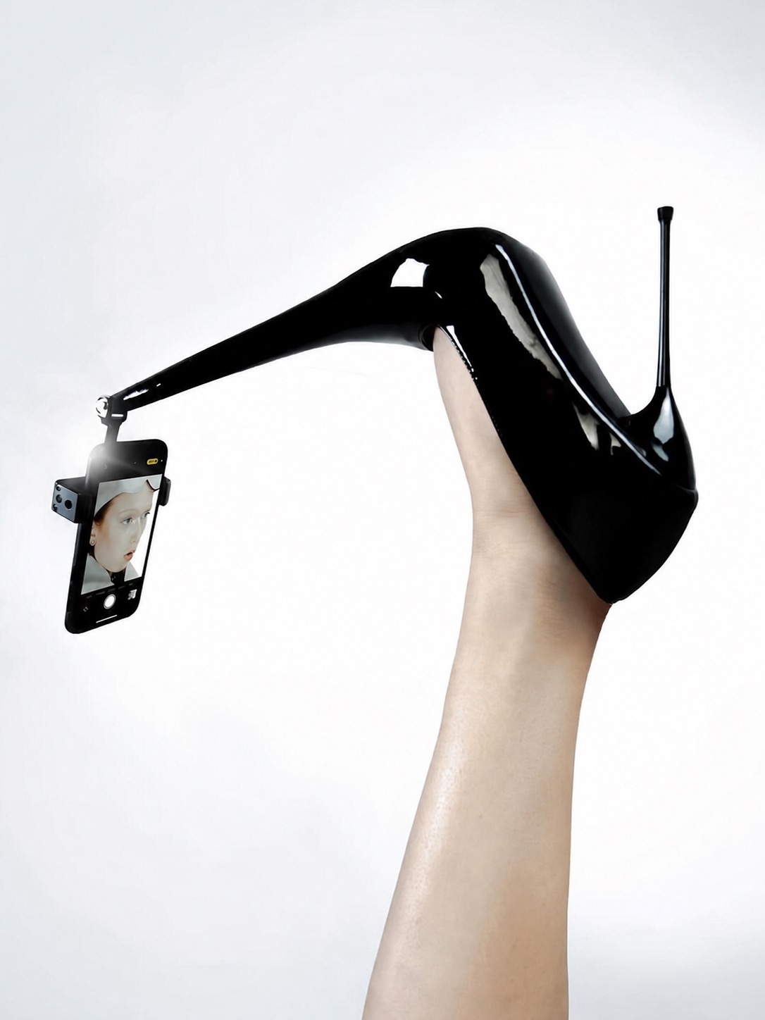 A black heel fitted with a phone-like extension against a white background.