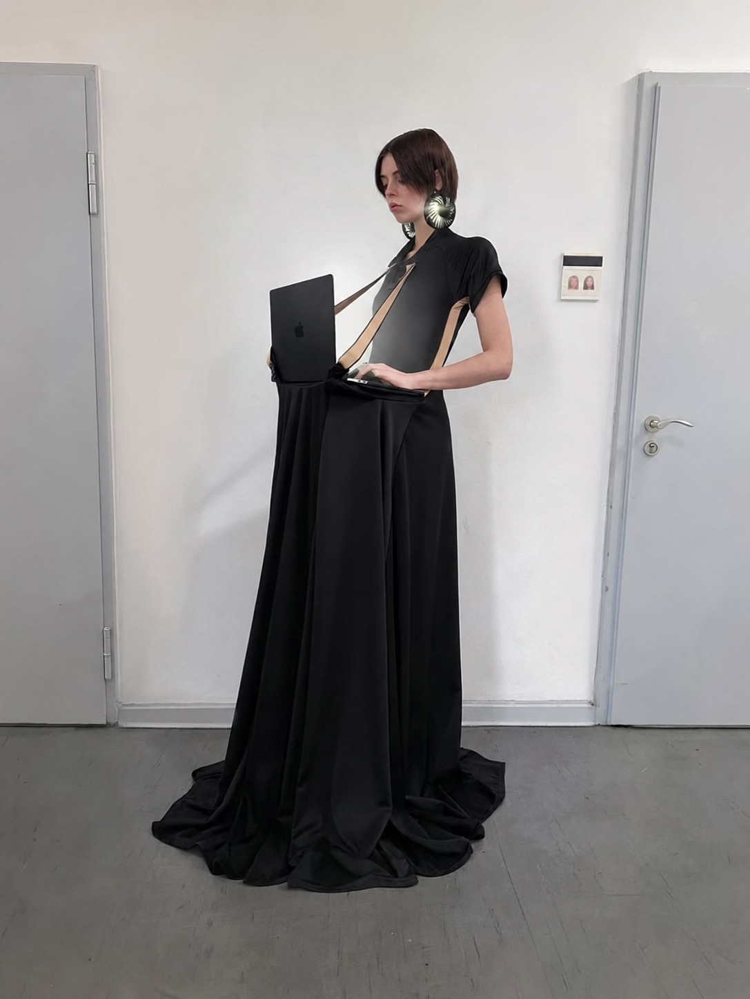 A black dress built around a laptop harness and metallic ear devices.