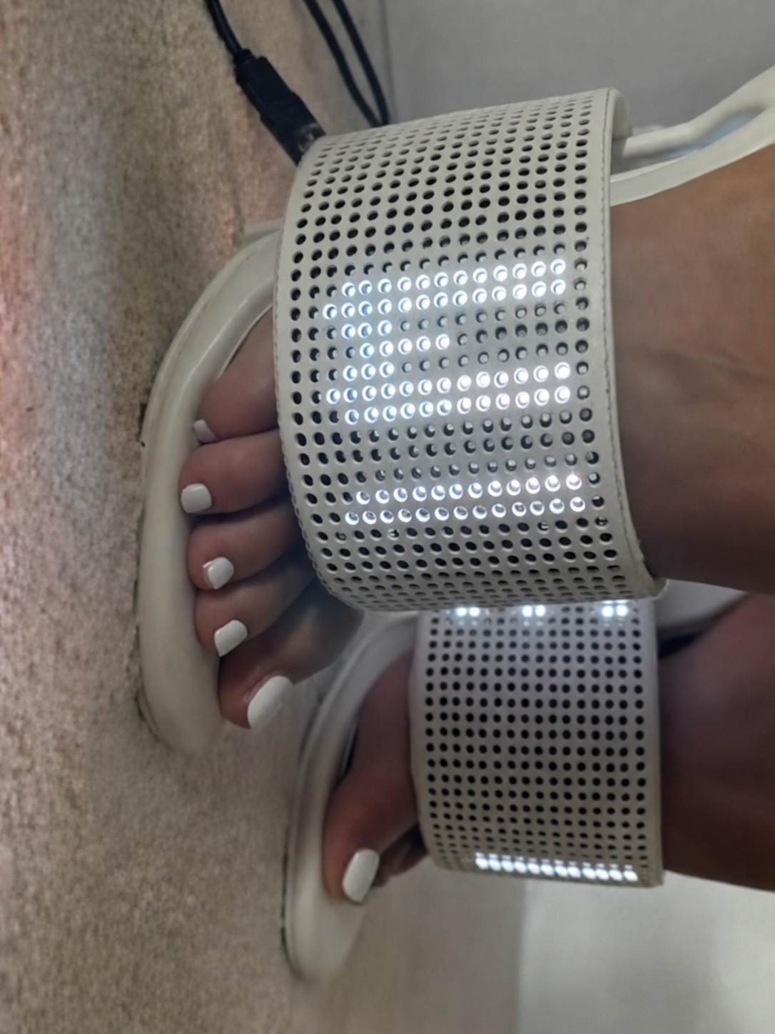 A close-up of white LED footwear with perforated panels and glowing lights.