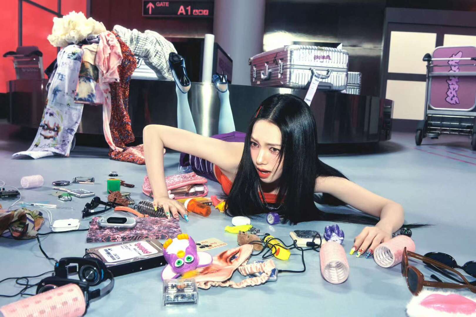 aespa member posed among scattered Y2K objects, gadgets, plush items, and accessories