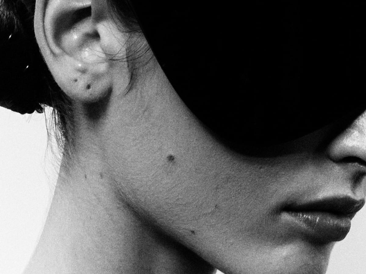 Black-and-white close-up of a model wearing an oversized futuristic visor near the ear.